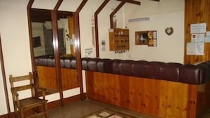 Una habitación con un banco de madera, una pequeña mesa de madera y un tablón de anuncios.