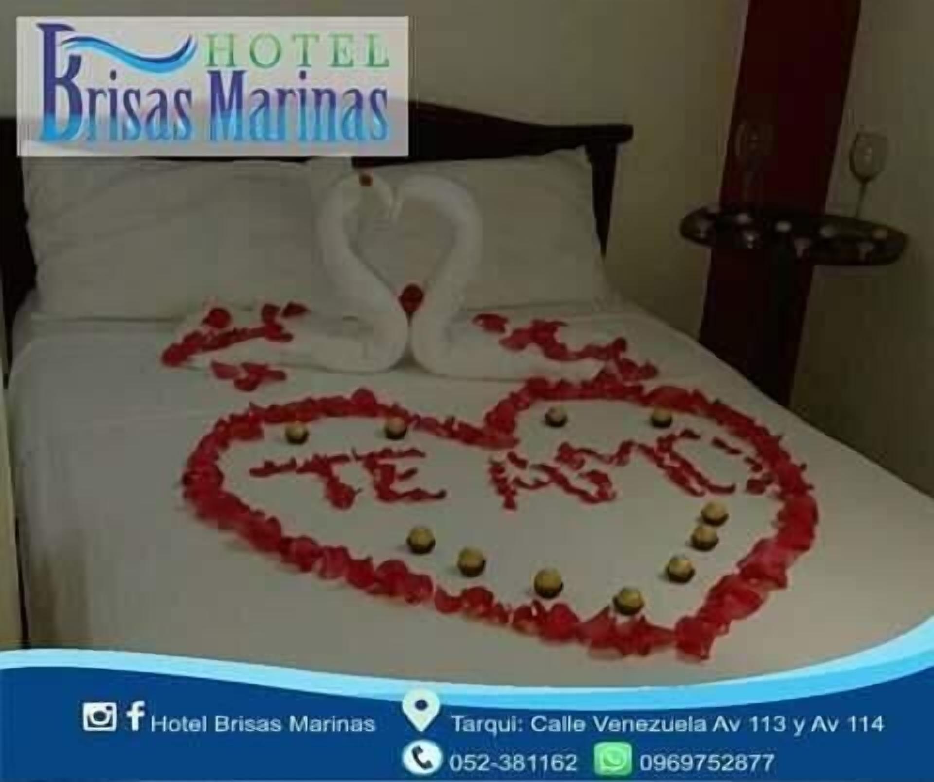 A hotel room with a bed decorated with a heart made of rose petals and two swans.