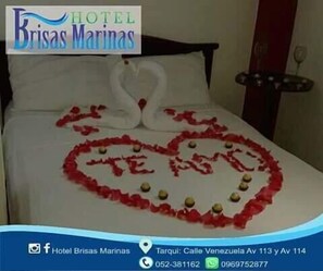 A hotel room with a bed decorated with a heart made of rose petals and two swans. - Hotel Brisas Marinas (Manta)