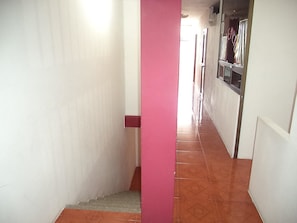A narrow hallway with a red pillar, tiled floor, and a window on the right. - Hotel Brisas Marinas (Manta)