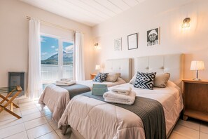 A hotel room with two beds, a balcony, and a view of mountains. - Riviera Fueguina Apartments (Ushuaia)