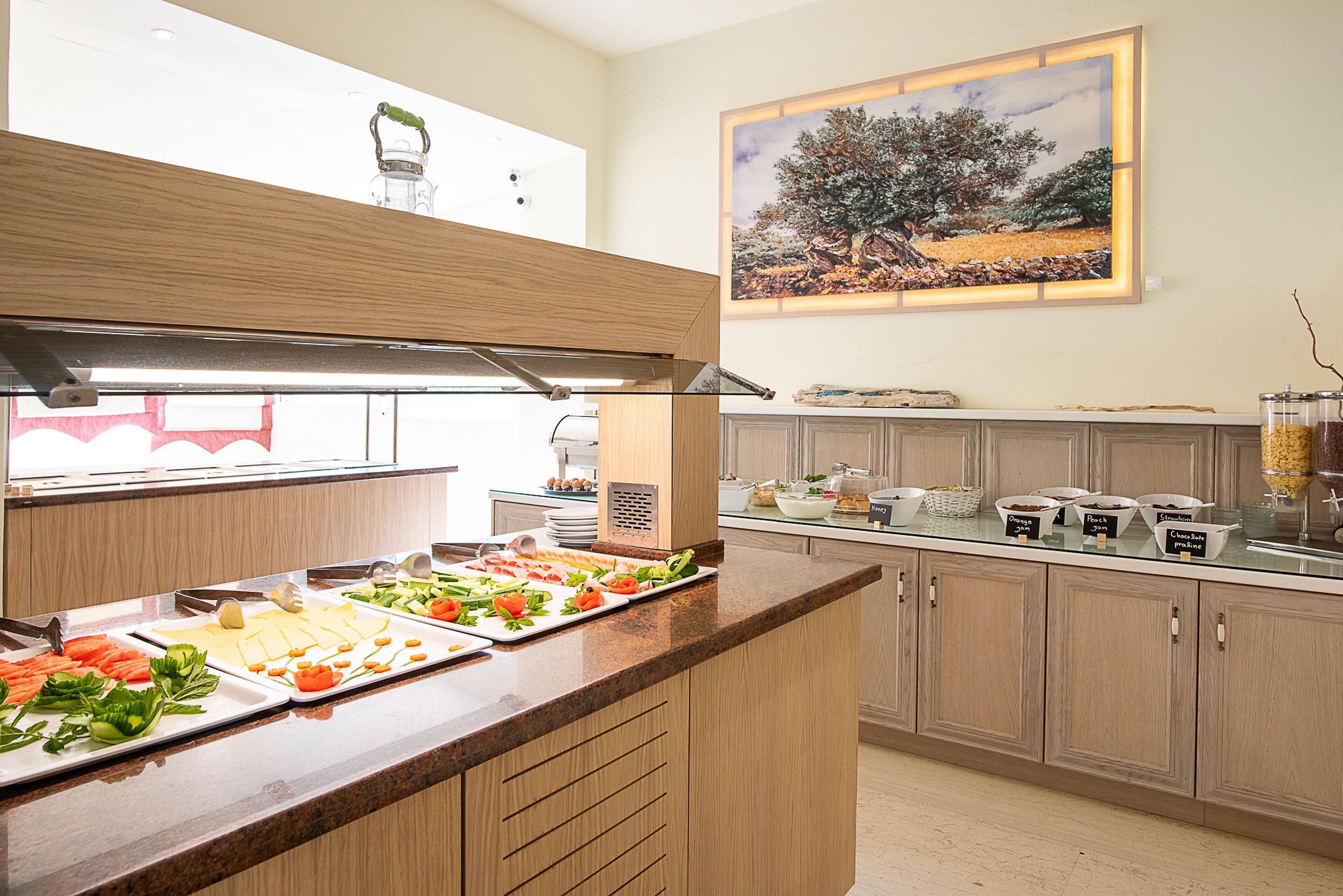 A kitchen with a buffet setup, including various food items and a painting on the wall.