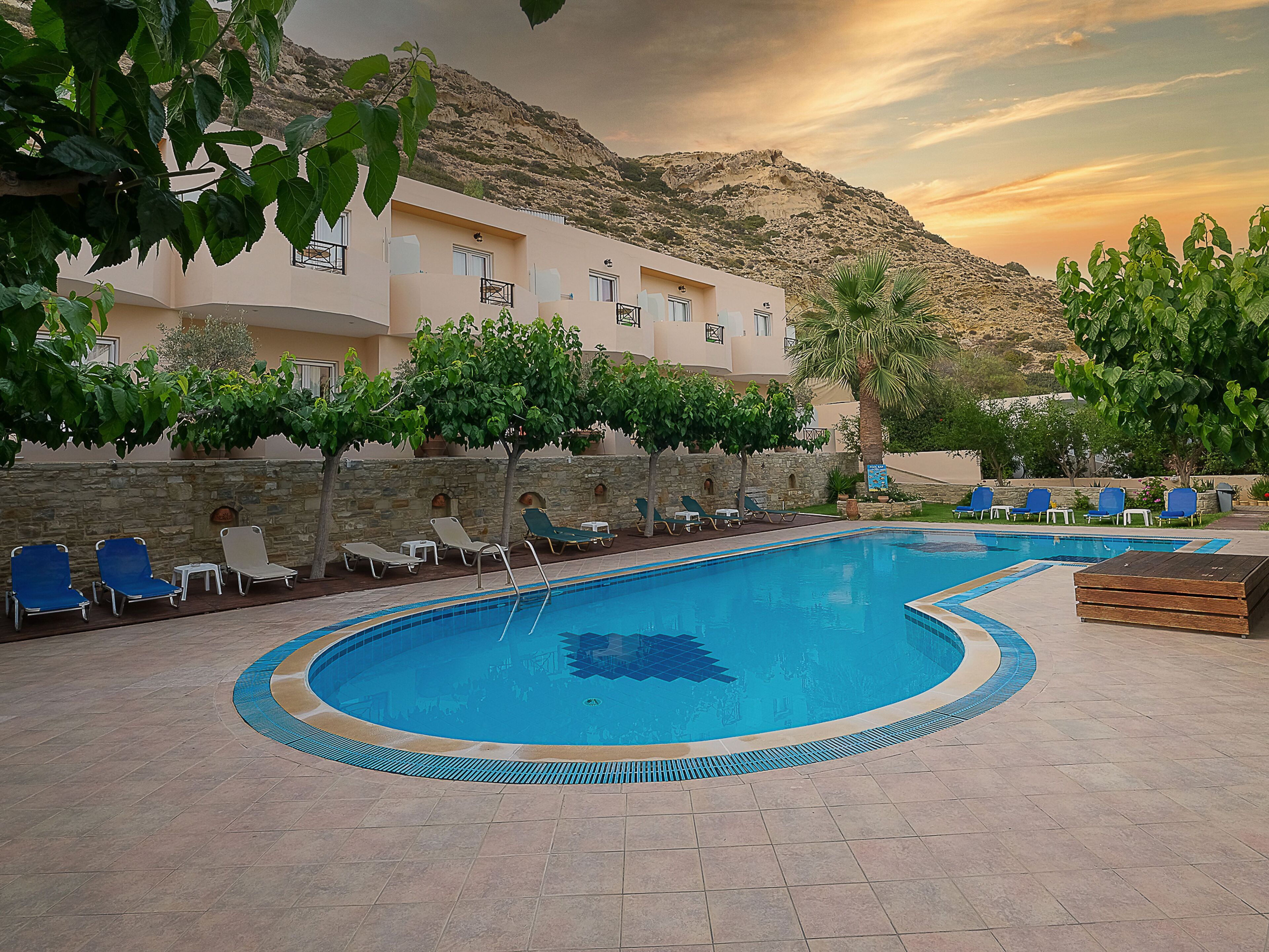 A pool area with lounge chairs and a stone wall.
