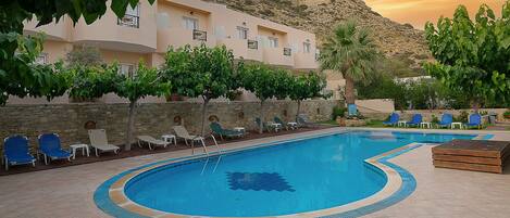 A pool area with lounge chairs and a stone wall.