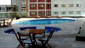 A rooftop pool area with lounge chairs and tables, surrounded by a high-rise building. - Arriendos IH Palmetto Eliptic (Cartagena de Indias)