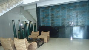 A modern living room with wicker furniture, a glass coffee table, and a blue-tiled wall. - Arriendos IH Palmetto Eliptic (Cartagena de Indias)