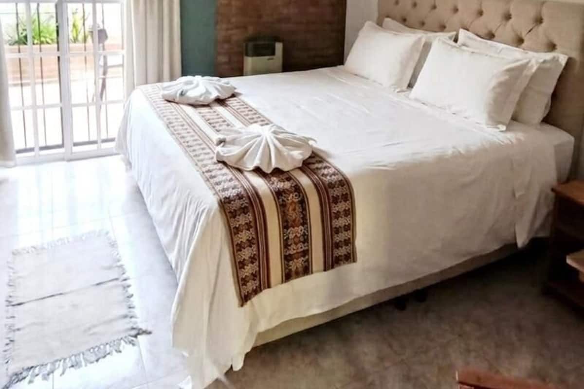 Un dormitorio con cama, ventilador de techo, ventana con cortinas y aire acondicionado instalado en la pared.