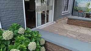 A hotel entrance with a covered patio area, a sign indicating a handicap-accessible entrance, and a variety of plants. - Altas Cumbres Hotel & Apart (Villa Carlos Paz)