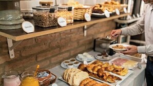 A buffet with various food items and a person serving. - Altas Cumbres Hotel & Apart (Villa Carlos Paz)
