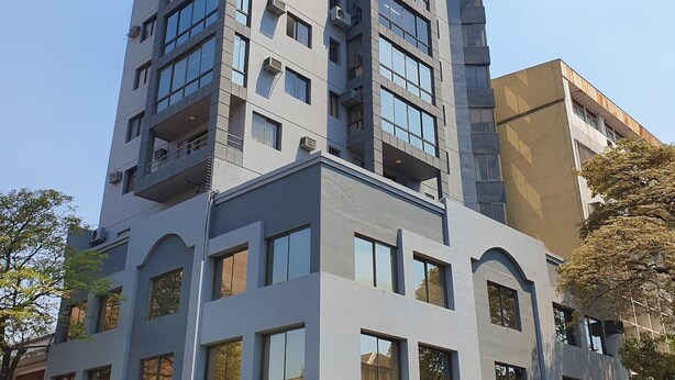 A multi-story building with commercial spaces on the ground floor, including a coffee shop and a restaurant. - Torre los Platanos (San Miguel de Tucumán)
