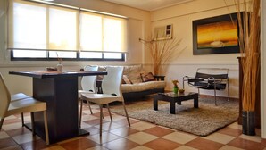 A living room with a sofa, chairs, a coffee table, and a dining area with a table and chairs. - Torre los Platanos (San Miguel de Tucumán)