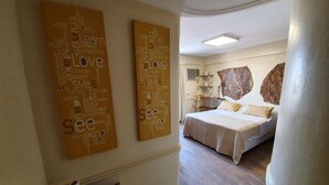 A hotel room with a bed, a desk, and a large rock decoration on the wall. - Torre los Platanos (San Miguel de Tucumán)