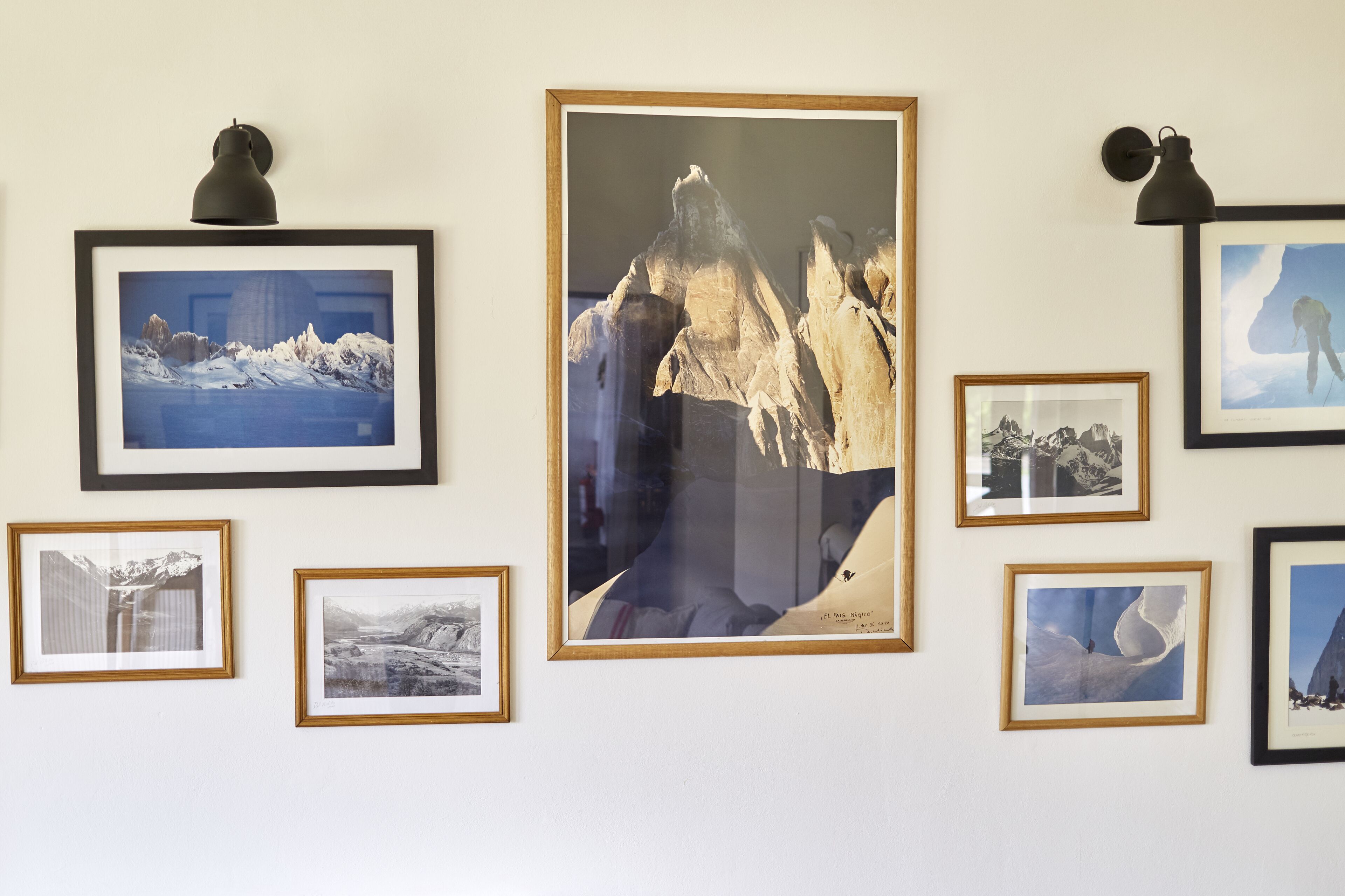 Una pared con varias fotografías enmarcadas de paisajes montañosos.
