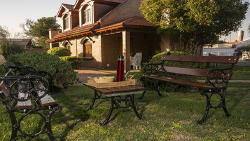 Una casa tradicional de ladrillo con techo de tejas, una banca y una mesa con un termo.