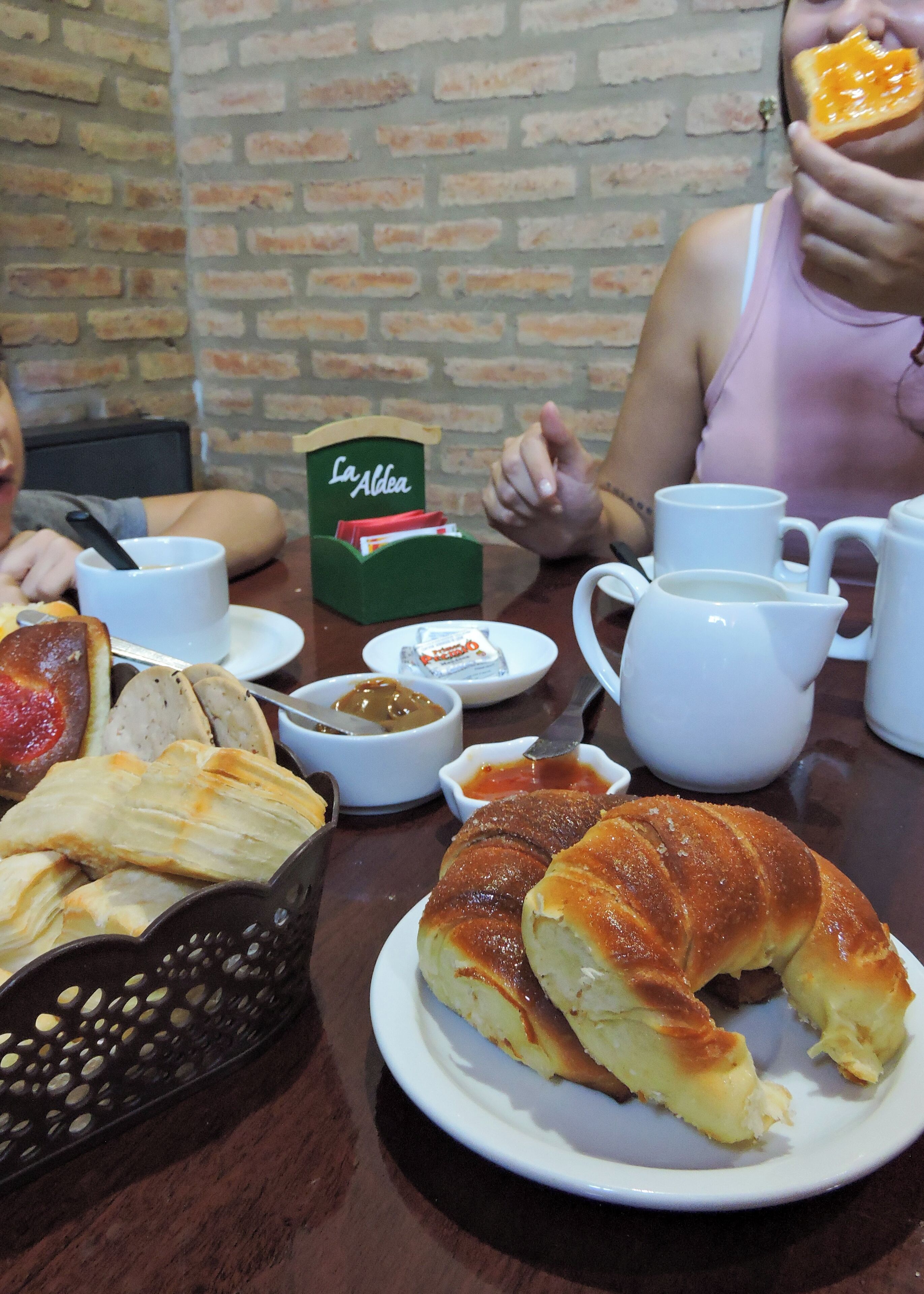 Ein Esstisch mit Speisen, einer Teekanne und einer Schachtel mit dem Aufdruck 'La Aldea'.