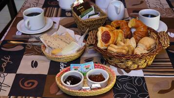 Una mesa de desayuno con café, pasteles y salsas.