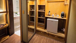 A compact bathroom with a wooden vanity, a small refrigerator, and a mirror. - Giardino di Pietra Hotel (Gramado)
