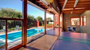 A pool area with wooden decking, a ping pong table, and lounge chairs. - Altaplaya Apart de Mar (Mar Azul)