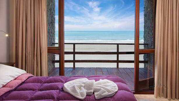 A bedroom with a bed, a view of the ocean, and a balcony with a railing. - Altaplaya Apart de Mar (Mar Azul)