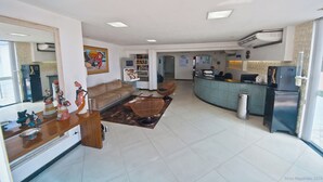 A spacious living area with a sofa, chairs, a coffee table, and a kitchen area with a refrigerator and sink.