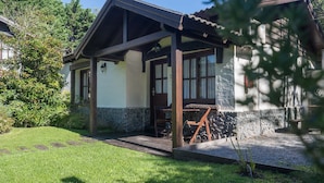 A house with a covered porch, stone foundation, and a small garden.
