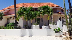 A building with a red-tiled roof, surrounded by palm trees and cacti. - Tu Casita (Noord)