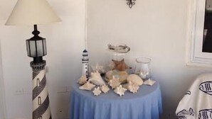 A room with a blue table covered with seashells, a lamp, and wall sconces. - Tu Casita (Noord)