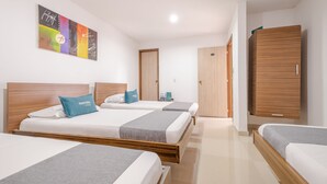 A hotel room with three beds, a wooden wardrobe, and a colorful abstract painting on the wall. - Ayenda 1501 Metropolitana Plaza (Bucaramanga)
