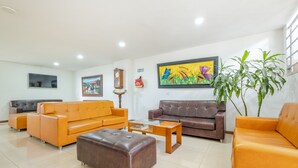 A spacious living area with two sofas, a coffee table, and a large painting on the wall. - Ayenda 1501 Metropolitana Plaza (Bucaramanga)
