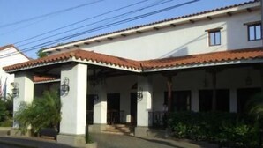 A two-story building with a tiled roof, a covered entrance, and a small porch area. - Hotel Nicarao Inn (Rivas)