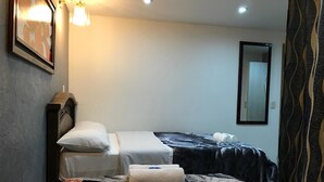 Habitación de hotel con dos camas, cabecera, espejo montado en la pared y cortina estampada.