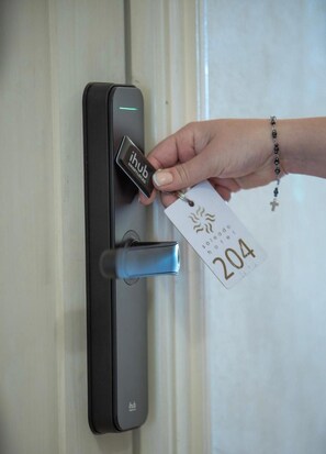 A hand inserting a key into a modern door lock with a card reader and a numbered card. - Hotel Pinamar Soleado (Ostende)