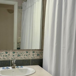 A bathroom with a white sink, a mirror, and a shower curtain.