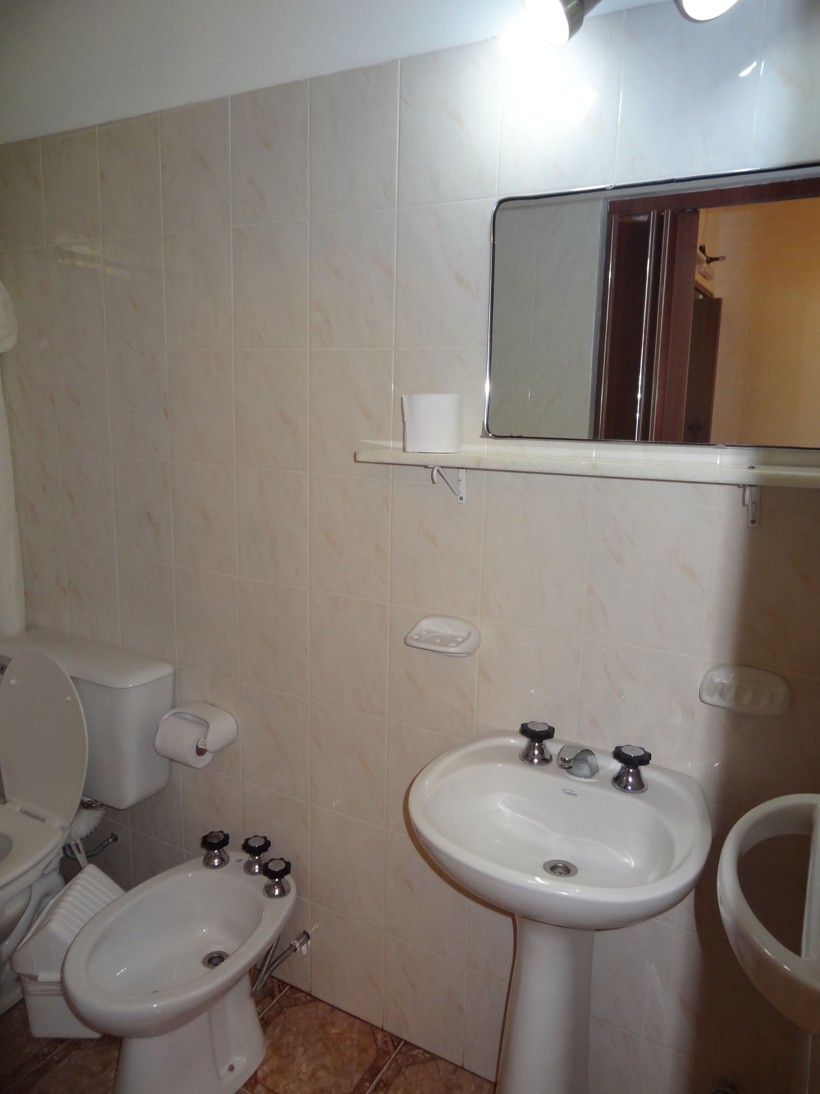 A bathroom with a toilet, bidet, sink, and mirror.