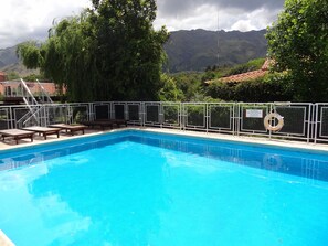 A swimming pool with a metal safety fence, wooden lounge chairs, and a lifebuoy. - Hostería Lida (Merlo)