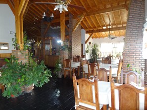 A restaurant with wooden beams, brick walls, and a black floor. There are tables and chairs set up for dining. - Hostería Lida (Merlo)