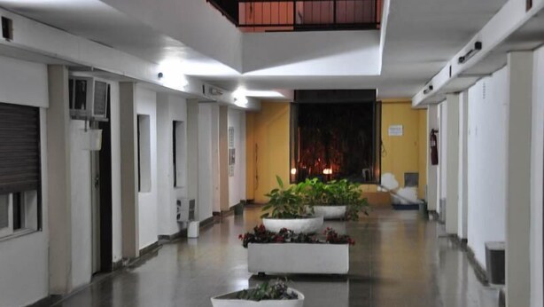 A hallway with white walls, a tiled floor, and potted plants. - Nuevo City Hotel (Rosario)