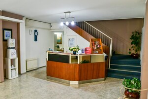 Un área de recepción con un escritorio de madera, un reloj, un radiador y una escalera.