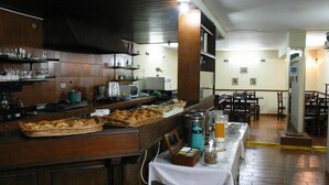 A restaurant with a buffet setup, including a variety of food items and beverages on the counter. - Nuevo City Hotel (Rosario)