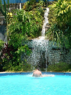A man in a swimming pool with a waterfall in the background. - Chanchamayo Inn Hotel (La Merced)