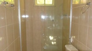 A bathroom with a glass-enclosed shower, a toilet, and a sink with a marble countertop. - Casa da Maisa (Porto Seguro)