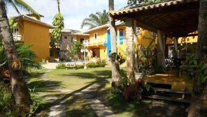 A courtyard with a pool, surrounded by palm trees and a covered seating area. - Casa da Maisa (Porto Seguro)