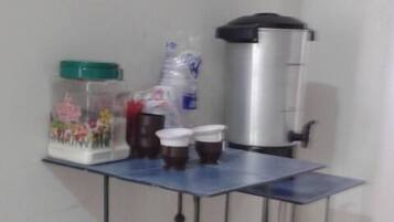 A small kitchen area with a coffee machine, a kettle, and a water dispenser on a blue countertop.