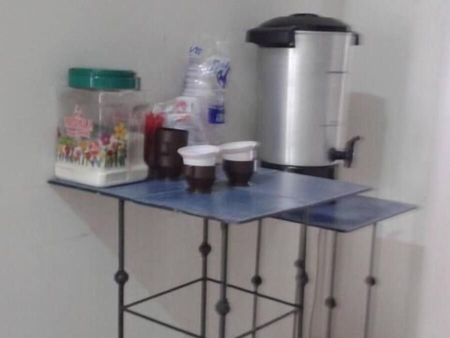 A small kitchen area with a coffee machine, a kettle, and a water dispenser on a blue countertop.