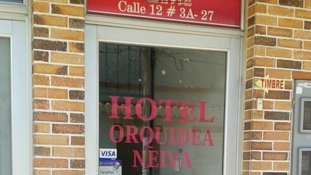 A hotel entrance with a glass door, a red sign above the door, and a 'Timbre' sign on the wall. - Hotel Orquídea Neiva (Neiva)
