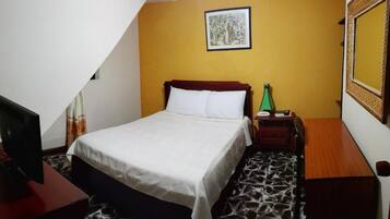Een hotelkamer met een bed, nachtkastje, lamp en een spiegel aan de muur.