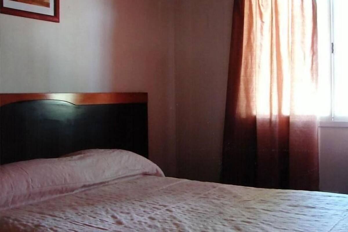 Une chambre à coucher avec un lit, une fenêtre avec des rideaux et un tableau encadré accroché au mur.