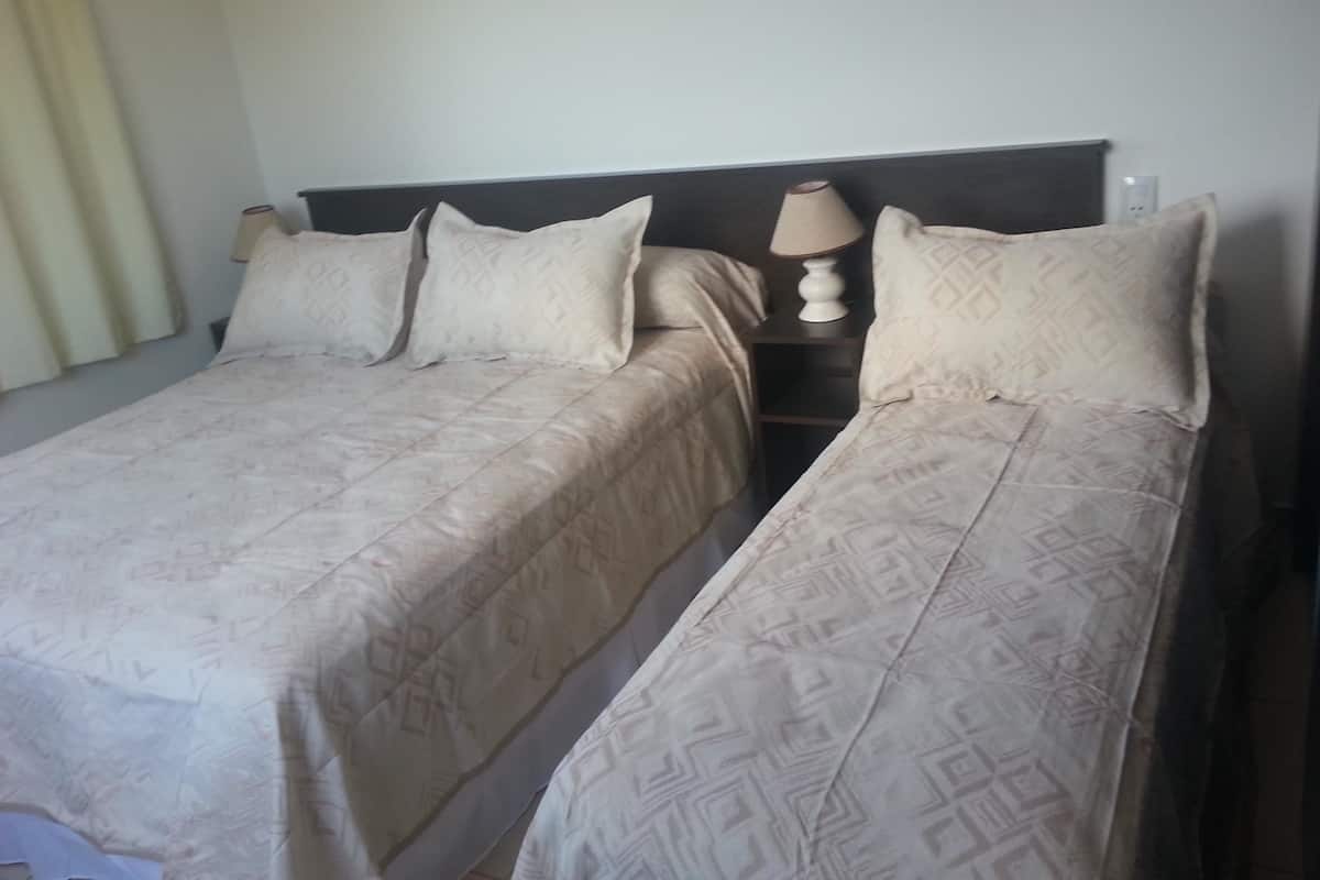 A double bed with a headboard, two pillows, and a bedside table with a lamp.