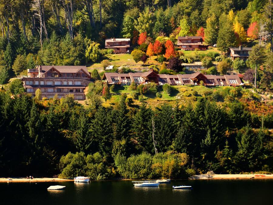 A lodge with multiple buildings surrounded by dense forest and a lake.