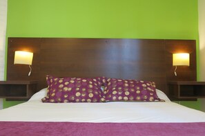 Relax in a spacious room with a large bed, dark brown headboard, and two wall-mounted nightstands.
